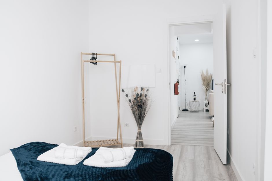 Bright and minimalist bedroom interior featuring an open door leading to a hallway and dried plants decor.